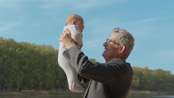 Grand-father Holding Baby Infant in Arms Outside. Grand Parent Bonding with Grand-child