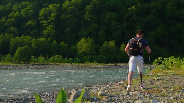 Male Traveller with Disabilities is Walking Alone Over Mountain River Shore