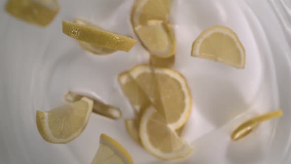 Sliced fresh lemons rain on yogurt in slow motion - High-angle shot