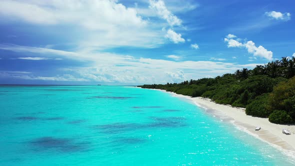 Wide angle flying tourism shot of a white paradise beach and blue water background in 4K