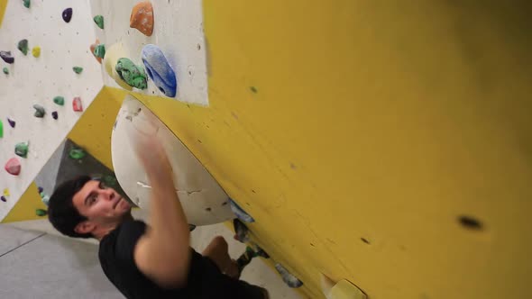 Close-up of a mans hands has he climbs in an indoor climbing gym.