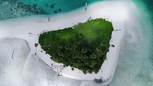 Ungraded cinematic overhead aerial view of a beautiful small island beach in the middle of the ocean