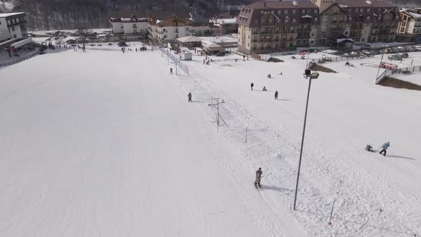 Flying over Skiers skiing climb a yoke on a mountain. people going skiing and snowboarding