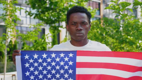 Close Up Afroamerican Man Holding an American Flag and Looks Camera