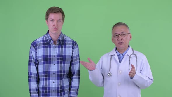 Stressed Mature Japanese Man Doctor with Young Man Explaining Something Together