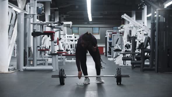 An Africanamerican Woman Disassembles the Dumbbell in the Gym