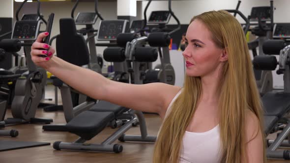 A Young Beautiful Woman Takes Selfies in a Gym