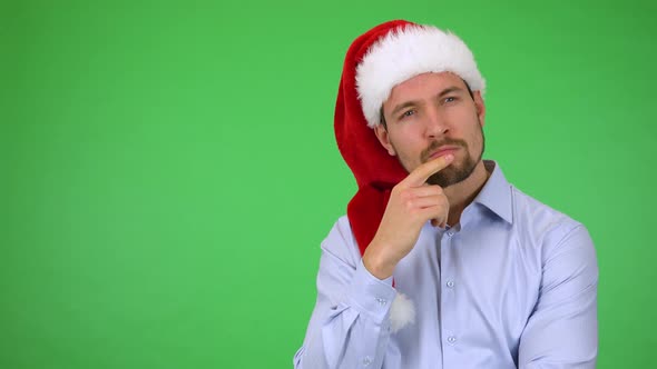 A Young Handsome Man in a Christmas Hat Thinks About Something - Green Screen Studio