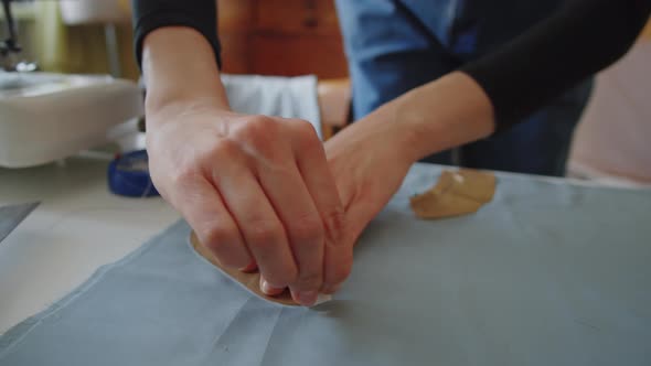 Hands of Dressmaker Outlining Sewing Pattern on Fabric with Chalk