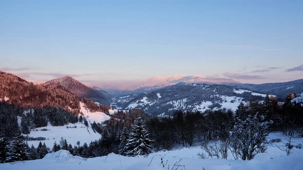 Winter frosty forest landscape, setting sun, paints pleasant color tones on spruce hills,