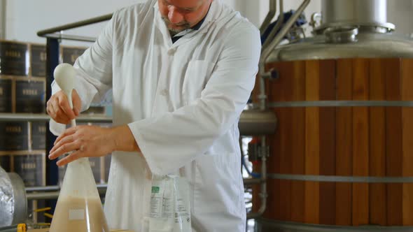 Male worker stirring liquor in flask 4k