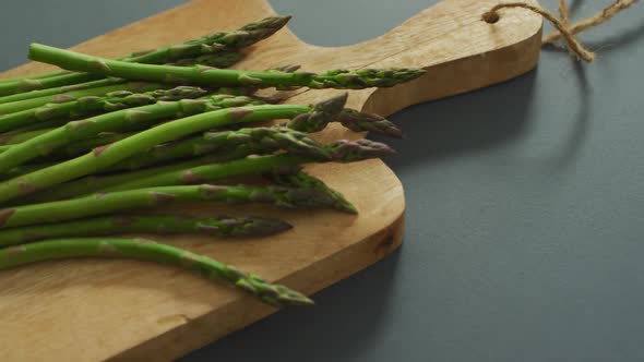 Video of asparagus on wooden chopping board over grey background