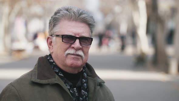 Cheery Senior Man in Dark Sunglasses Smiling and Standing in a Street in Slo-mo  