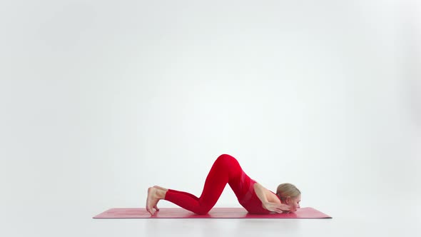 Beautiful Young Woman Wearing Red Sportswear Doing Yoga or Pilates Exercise Pose on White Background