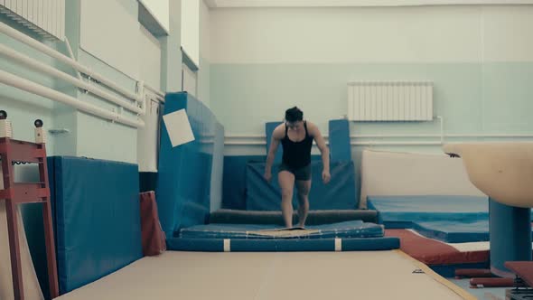 Athletic Girl in Gym Doing Back Somersault