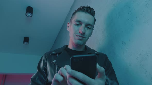 Portrait of Man Using Smartphone at Night Over Neon Lights