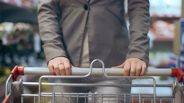 Beautiful Young Woman with Trolley Walking in Supermarket