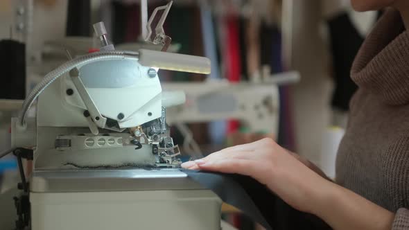 Stitching on sewing machine. Tailor sews on sewing machine. Close-up of woman's hand