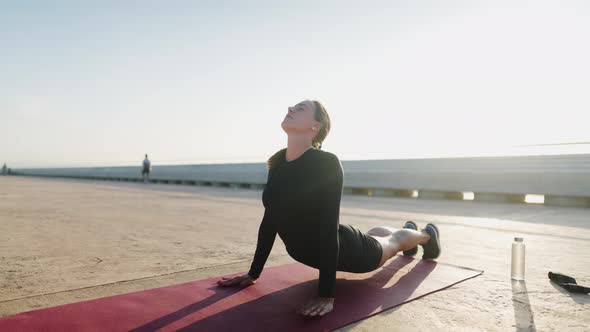 Slim Woman Stretching on Embankment