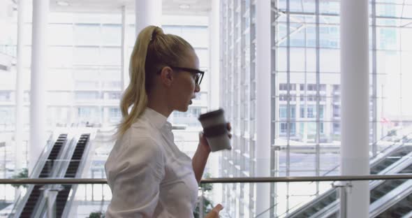 Side view of Caucasian Businesswoman using mobile phone and drinking coffee in the lobby at office 4