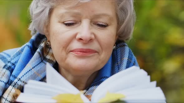 Elderly Woman Walks in the Park in Autumn and Relaxes.