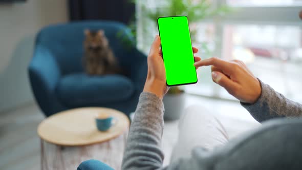 Woman at Home Using Smartphone with Green Mockup Screen in Vertical Mode