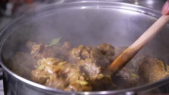 Cooking Jamaican curry goat.  Stirring the pot.