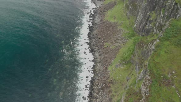 Drone shot from above of  coast cliff in isle of skye in scotland, clear blue water and green grass