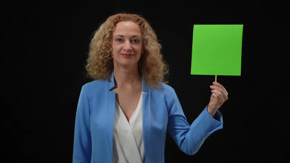 Portrait of Smiling Woman Looking at Camera Shaking Head Yes Holding Green Mockup Sign in Hand