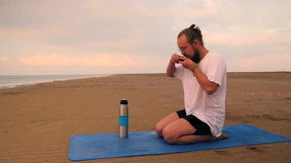 Man Drinks Tea at Beach