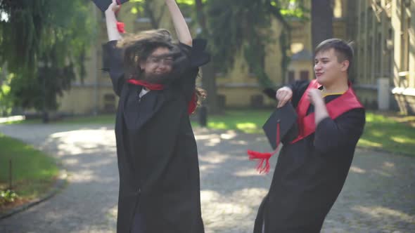 Satisfied Excited Graduates Dancing on Sunny Morning at University Campus Smiling