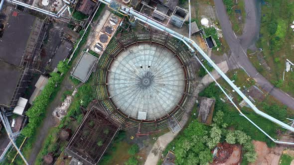 Aerial top-down view of storage tank at abandoned steel factory. Rotating high above