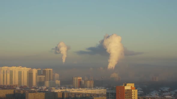 City Pipes Emit Steam Into the Atmosphere Against the City Skyline