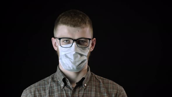 Young Man in Medical Mask Against Covid-19 Looks at Camera. Coronavirus Outbreak