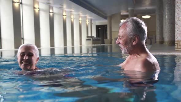 Joyful Elderly Couple Relaxing in Spa Hotel Pool