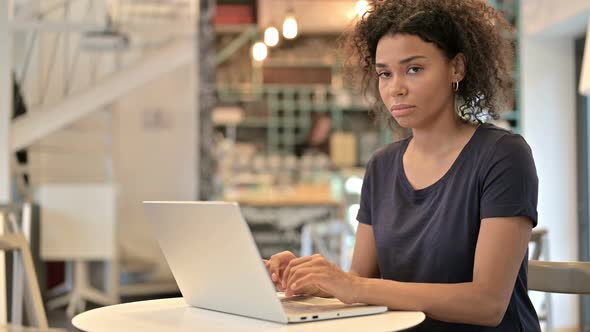 Young African Woman with Laptop Pointing with Finger 