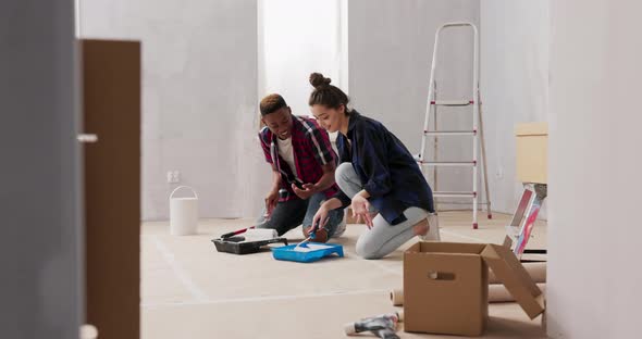 Two Happy Young People in Love are Renovating Their First Purchased Apartment They are Kneeling on
