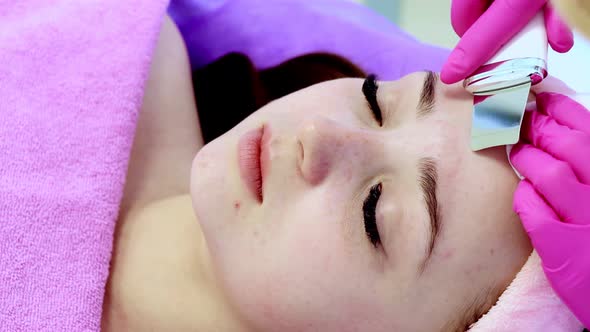 Ultrasonic scrabbing. Young woman receiving ultrasound cavitation facial peeling cleansing
