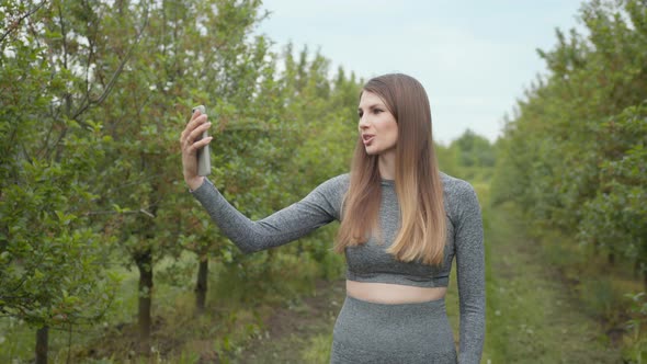 A Modern Sports Woman Takes Pictures on the Nature Smartphone Recording a Video