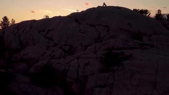 Inukshuk on Rocky Pine Tree Island at Sunset, Drone Aerial Wide Pedestal Up. Reveal of Blue Lake, Co