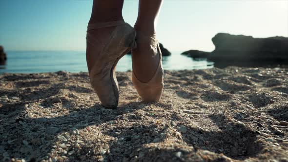 Close Up of Ballet Dancer's Feet. She Practices Exercises on Sandy Beach. Woman's Legs in Pointe