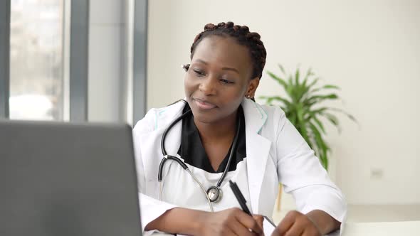 African Woman Doctor Having with Headset Chat or Consultation on Laptop