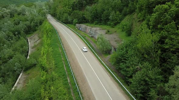 Aerial Top Down  View of White Car Driving on Rural Road in Forest