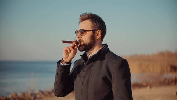 Bearded Man In Sunglasses with  Smoking Cigar. Relaxing Businessman In Sunglasses Smoke Cigar.