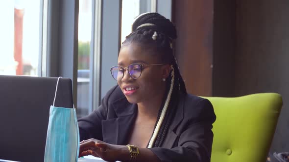 African American Young Woman Communicating By Conference Call Speak Looking at Computer in Cafe