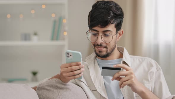 Spaniard Arabic Young Man Guy with Glasses Sitting at Home Shopping Online Makes Internet Order Book