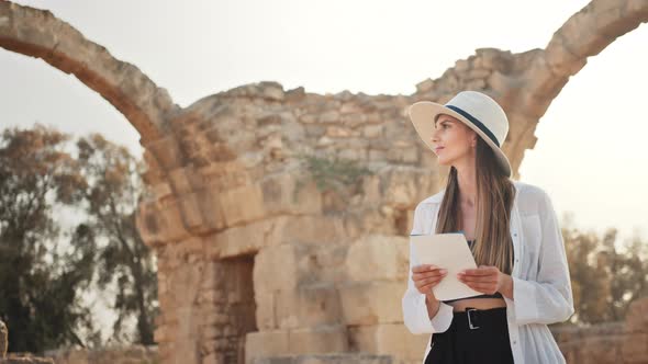 Woman in White Hat and Casual Clothes Walking Among Ruined Ancient Temple with