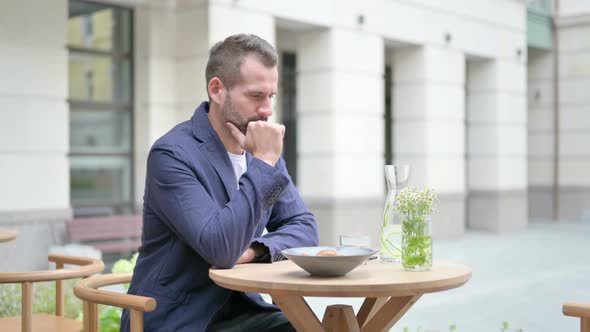 Brainstorming Man Sitting in Outdoor Cafe and Thinking