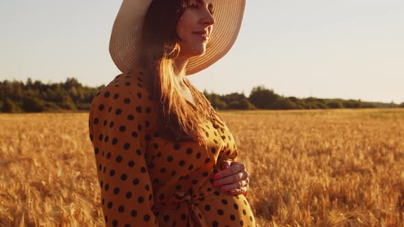 Pregnant woman in the rays of the sunset in the field