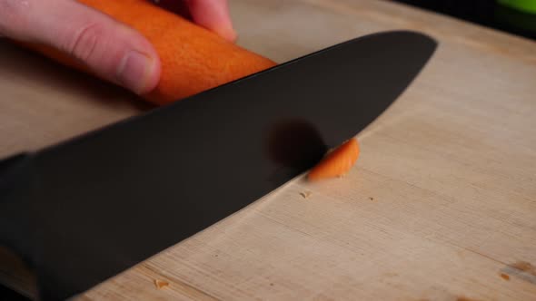 Cutting of the front and back of a carrot in slow motion on a chopping board.